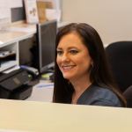 Meet the  {PRACTICE_NAME} Staff-Jennifer Lybrand smiling at the front desk